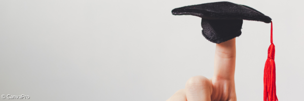 ein Miniatur-Doktorhut auf einem Zeigefinger