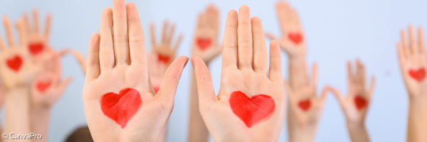 Viele hochgereckte Handflächen, in die rote Herzen gemalt sind