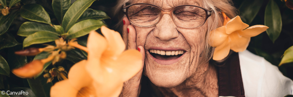 eine ältere Dame steht zwischen orangenen Blumen und lacht