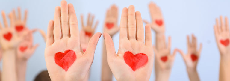 Viele hochgereckte Handflächen, in die rote Herzen gemalt sind