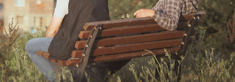 zwei Menschen sitzen auf einer Parkbank im Grünen