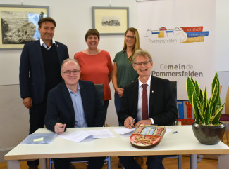 fünf Menschen am Tisch bei der Unterschrift zur Betriebsübergabe